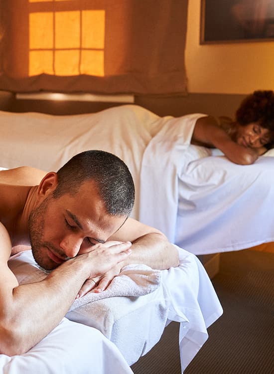 Un uomo e una doppia sdraiati su due lettini massaggio.