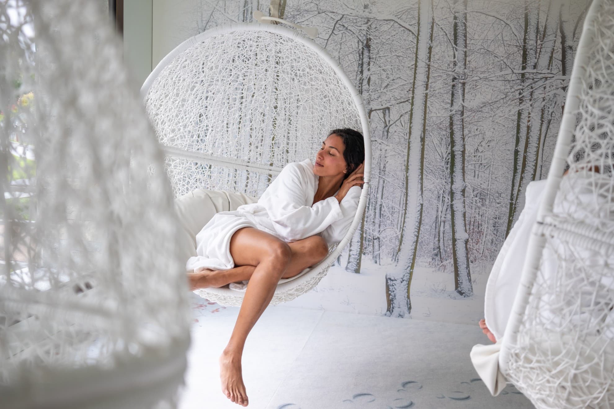Donna che dorme in una sala relax con pareti che ricordano la neve, su una poltrona sospesa.